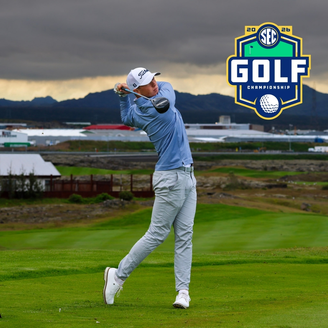 Golfer in light blue shirt mid-swing on a green golf course with a large SEC Golf Championship logo in the sky-right background.