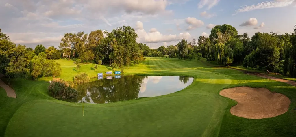 Scenic golf hole with a green, water hazard, and a sand bunker surrounded by trees