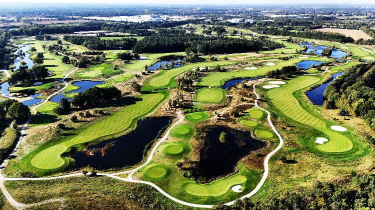 Aerial view of a golf course with winding fairways, greens, sand traps, and water hazards.