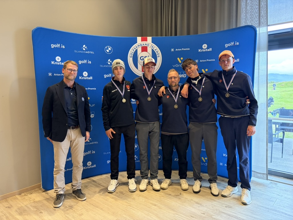 Six people pose in a line for an award photo, each wearing a medal in front of a blue sponsor backdrop.