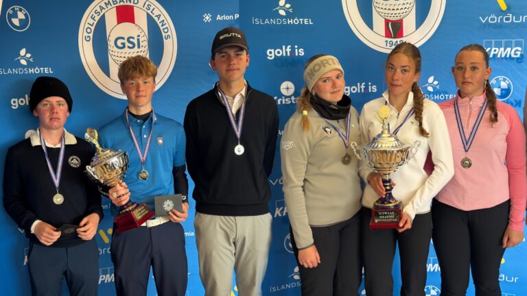 Six young athletes pose with medals against a blue sponsor backdrop, two holding large trophies in front of a golf event banner.