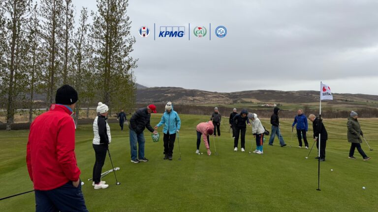 Group of people practicing putting on a golf green under a cloudy sky with sponsor logos visible above.