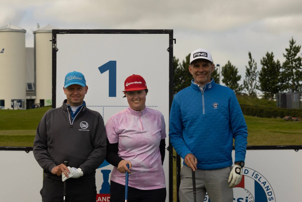 1-499A4458 - Golfsamband Íslands Three golfers pose in front of a large sign showing the number 1, each holding a golf club.