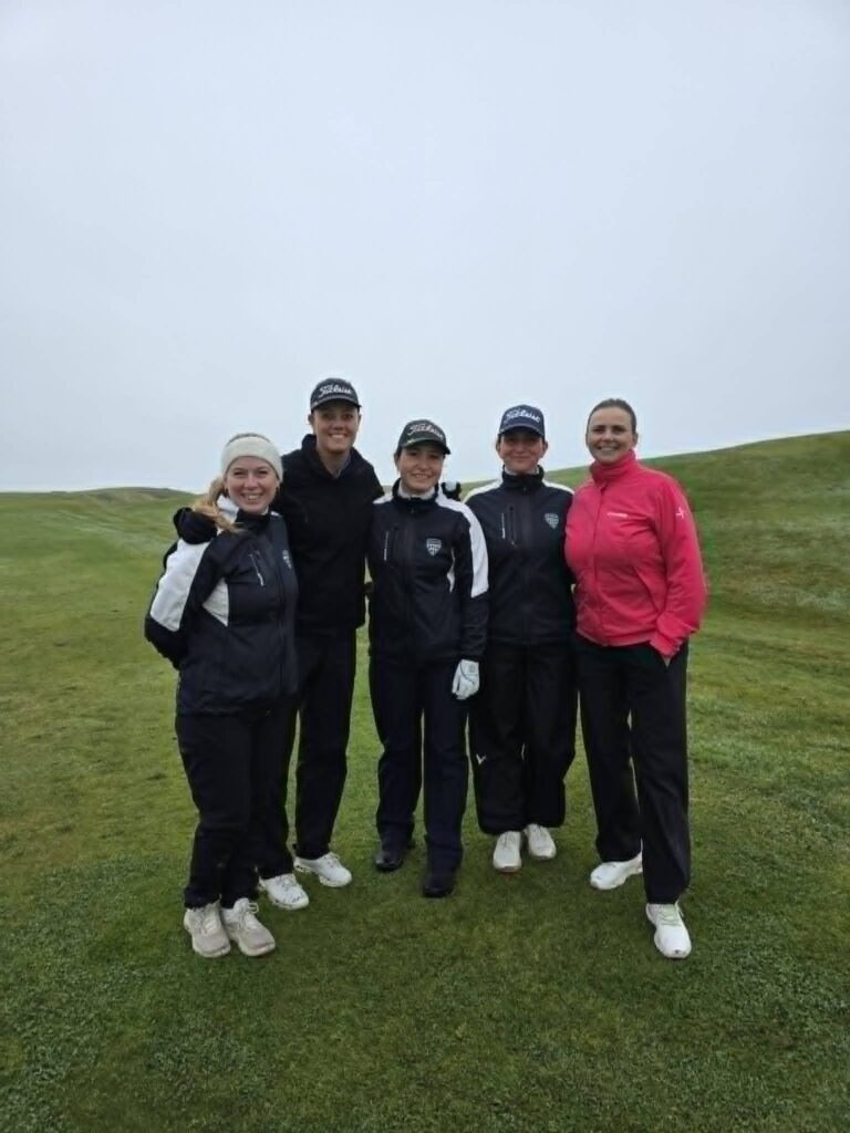777882461_1451687430101524_5589323245755290514_n - Golfsamband Íslands Five friends posing outdoors on a grassy hill, wearing jackets and caps, and smiling at the camera.
