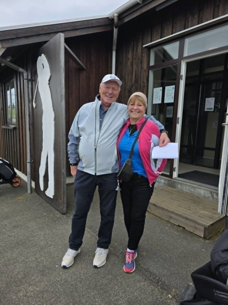 777899596_1451687030101564_8281341887791664093_n - Golfsamband Íslands Smiling older couple standing outside a wooden building with their arms around each other.