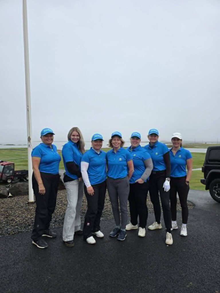 778565360_1451687280101539_4208304865345517057_n - Golfsamband Íslands Group of eight people in blue polo shirts and caps posing together outdoors under a cloudy sky