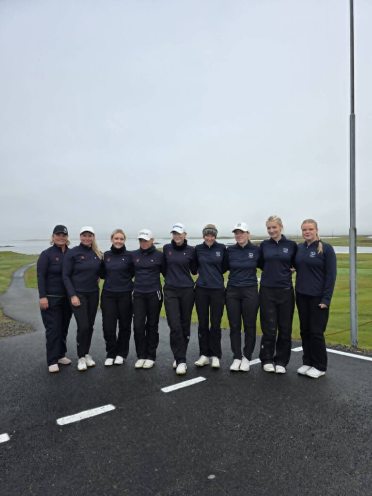 778874032_1451687286768205_1281510056884375621_n - Golfsamband Íslands Group of people in navy jackets standing in a line on a paved road outdoors, posing for a team photo.
