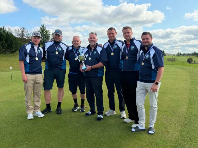 Seven golfers in matching blue uniforms with medals, posing together on a golf course with a trophy in the center.